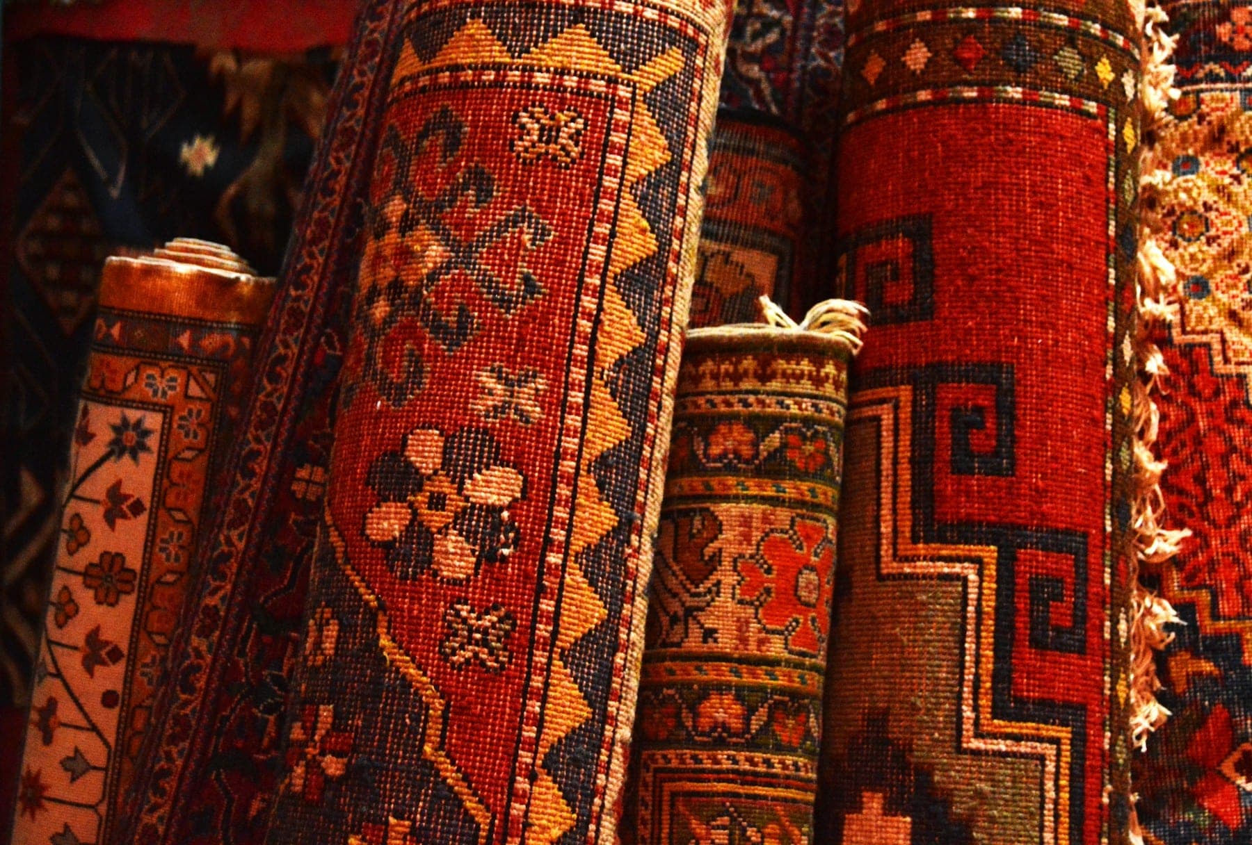 Standing rolled tribal rugs in brick red and saffron
