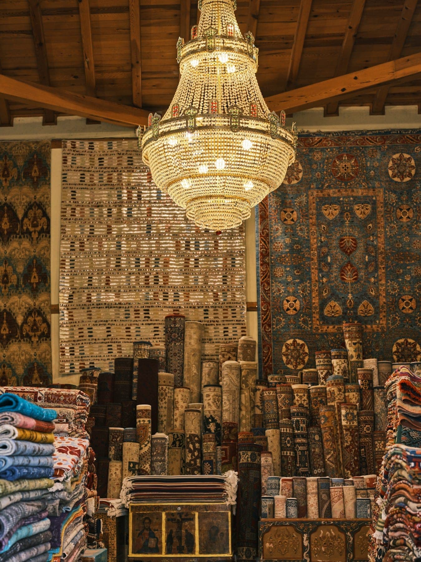 Carpet showroom with a crystal chandelier above rows of rolled rugs