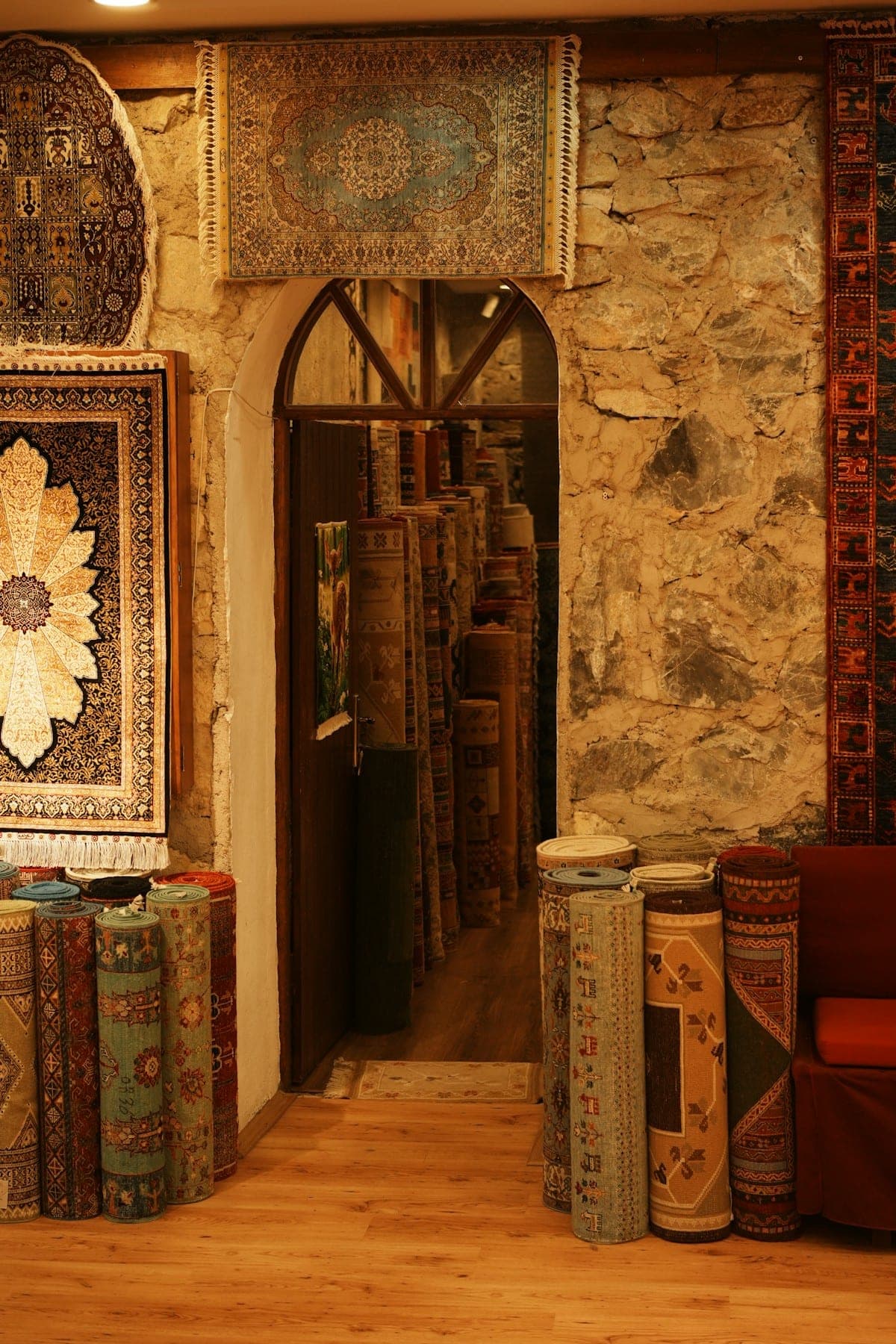 Stone-walled rug shop doorway lined with rolled carpets
