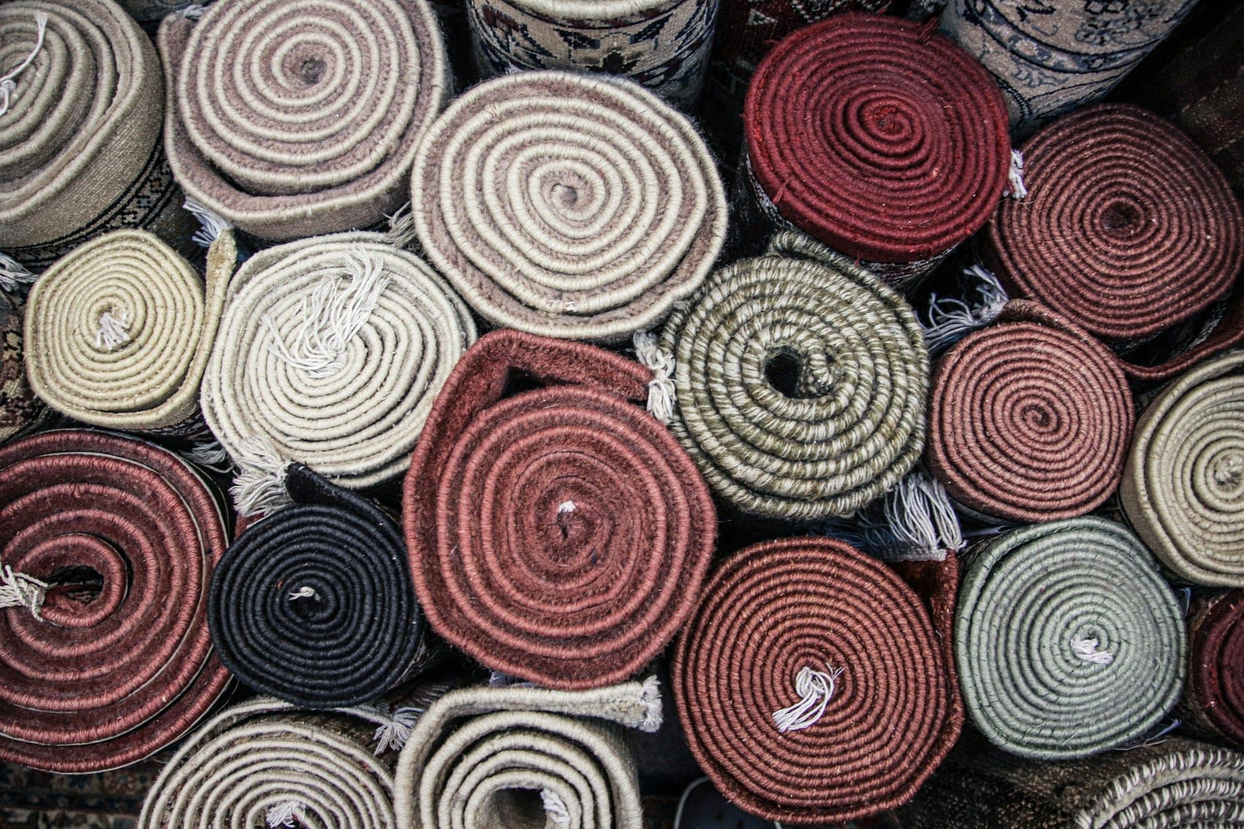 Wall of rolled rug ends in wine, ivory and sage