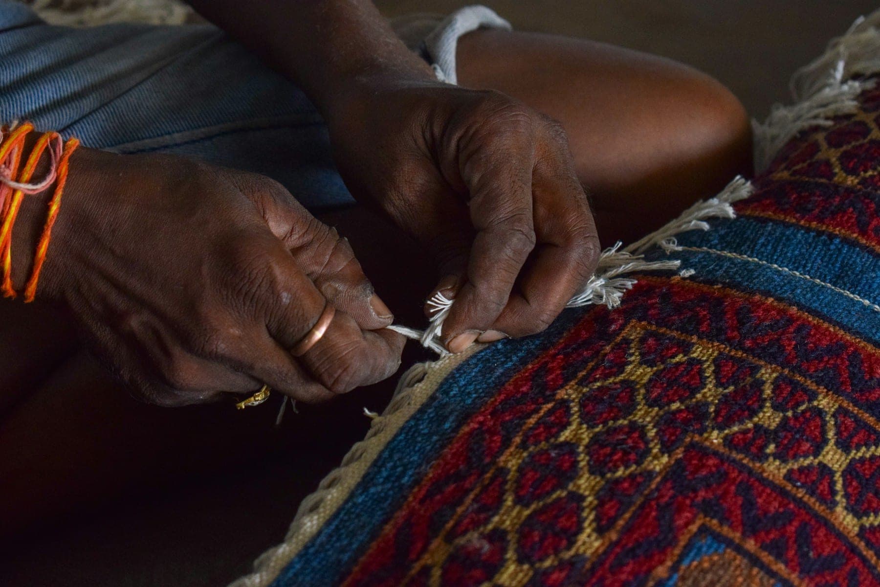 Artisan's hands finishing the edge of a hand-knotted rug