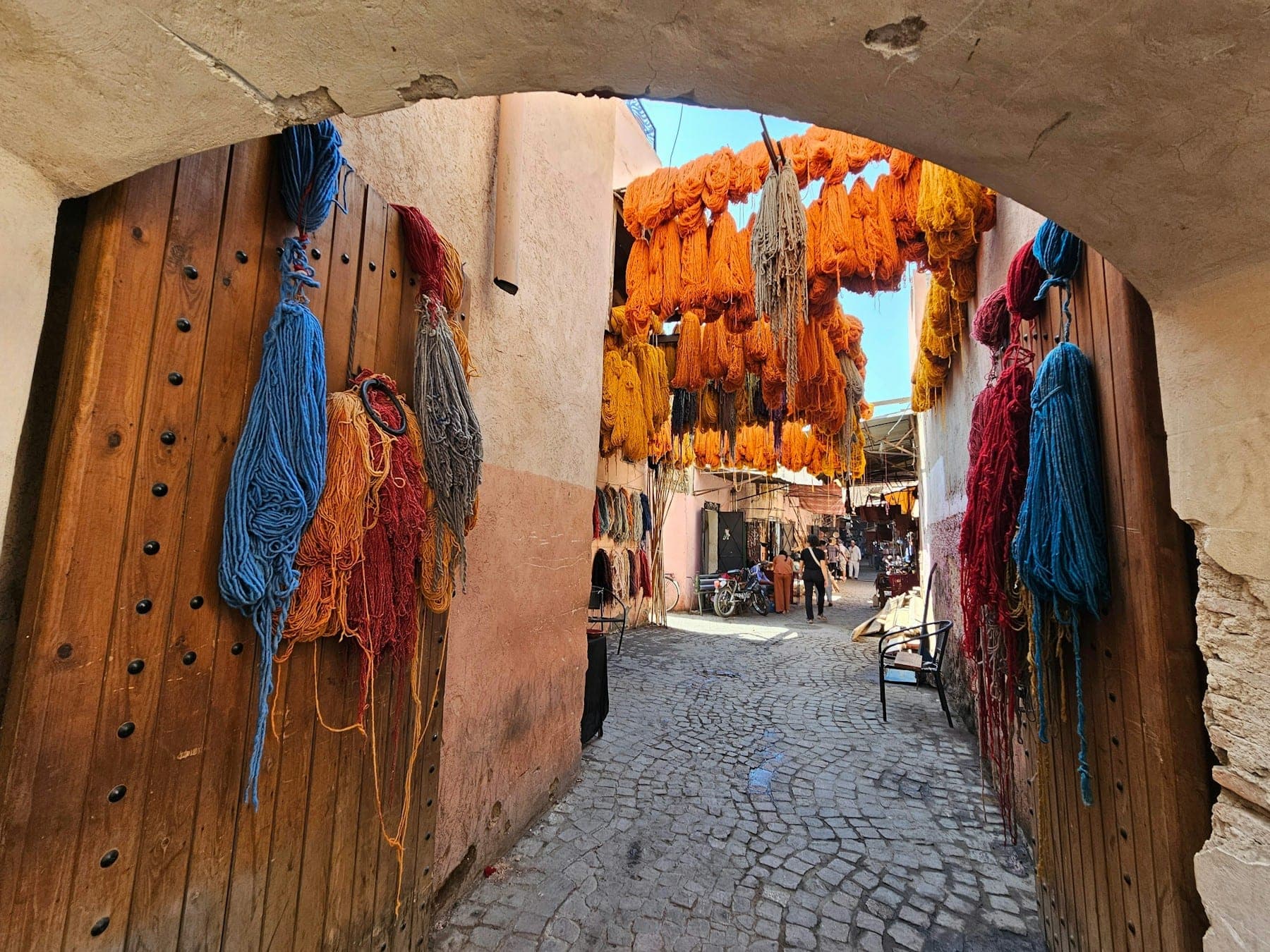 Freshly dyed wool hanging in a dyers' souk, seen through a wooden archway