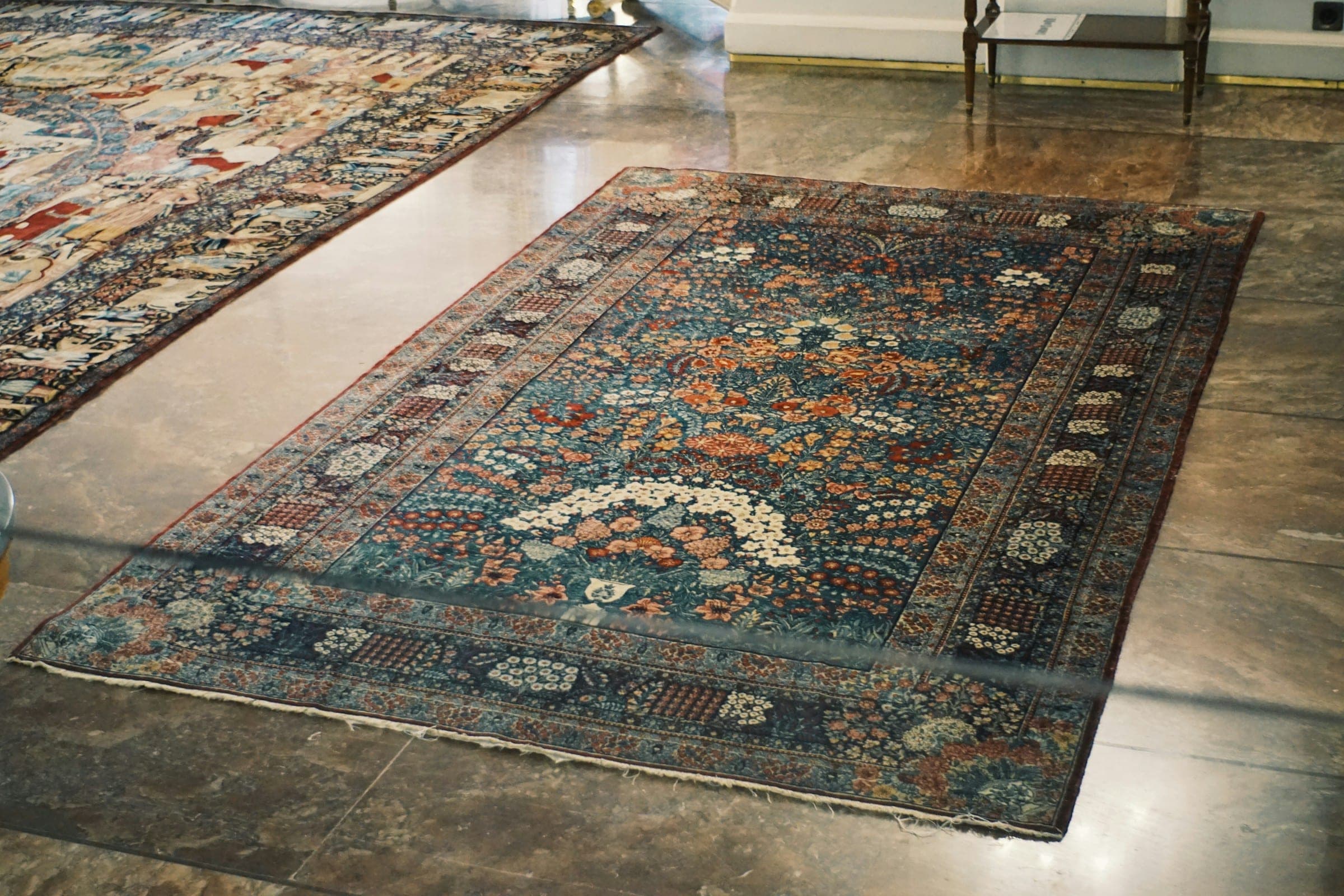 Ornate indigo and rust Persian rug laid on a polished stone floor
