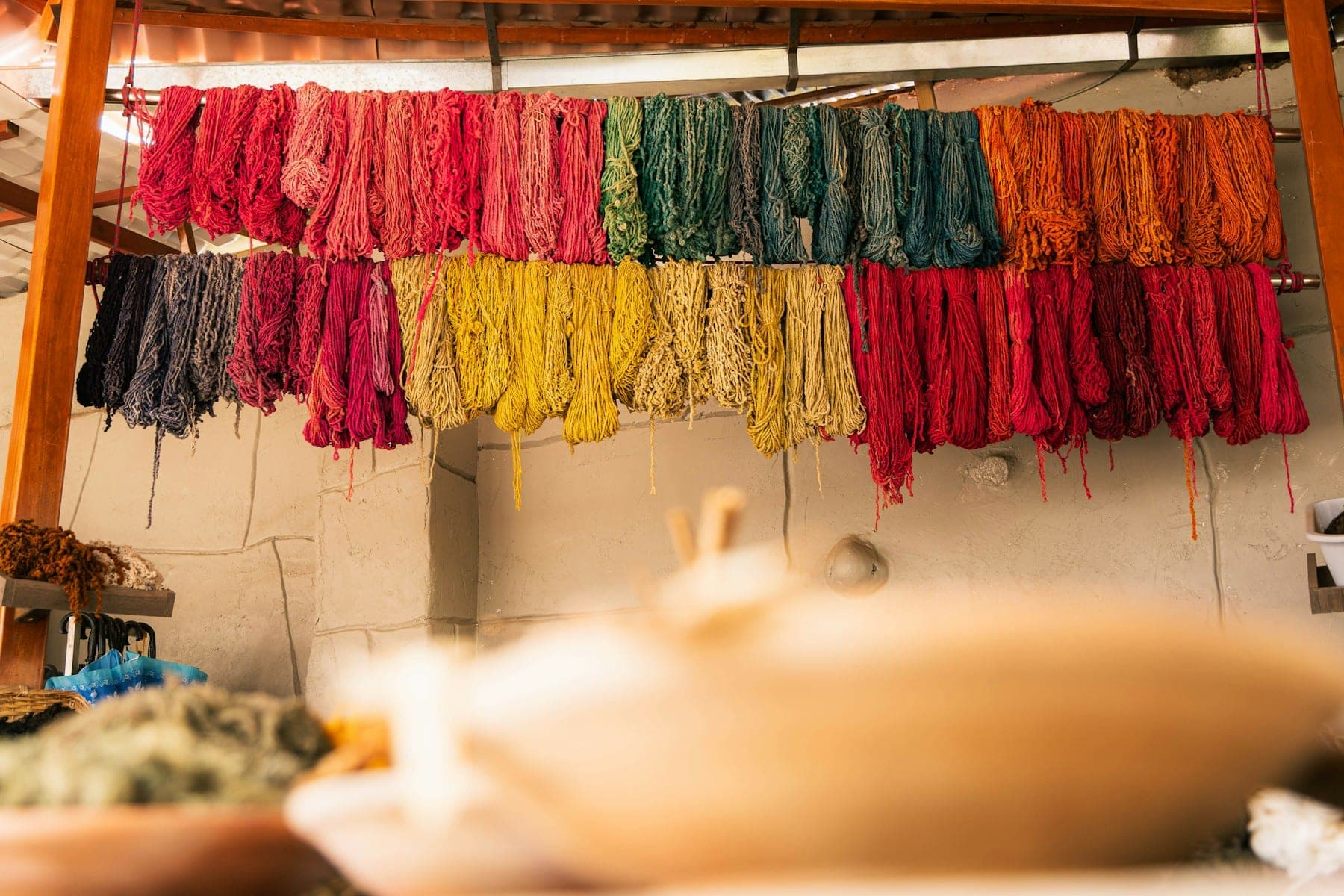Hand-dyed wool skeins in madder red, saffron and indigo drying on racks