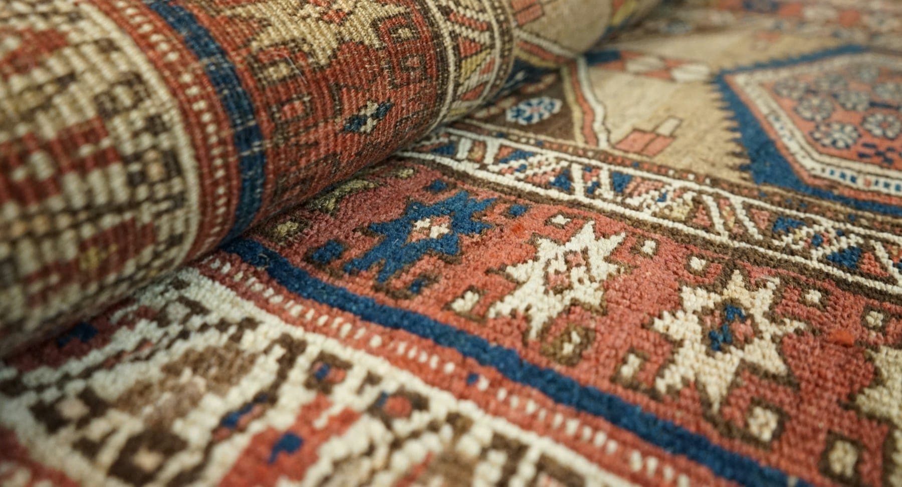 Rolled edge of a geometric Anatolian rug showing dense pile and star motifs